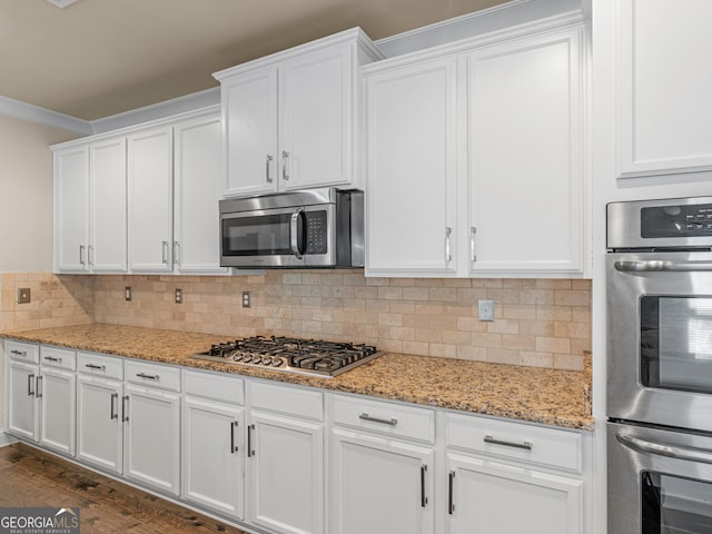 kitchen featuring light stone countertops, stainless steel appliances, white cabinets, decorative backsplash, and dark wood finished floors