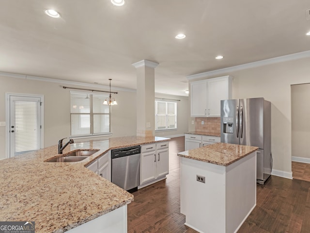 kitchen with appliances with stainless steel finishes, a center island, white cabinets, and a sink