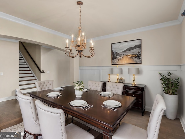 dining space featuring a decorative wall, an inviting chandelier, ornamental molding, wainscoting, and light wood-type flooring