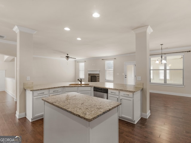 kitchen featuring a peninsula, hanging light fixtures, a sink, and white cabinets