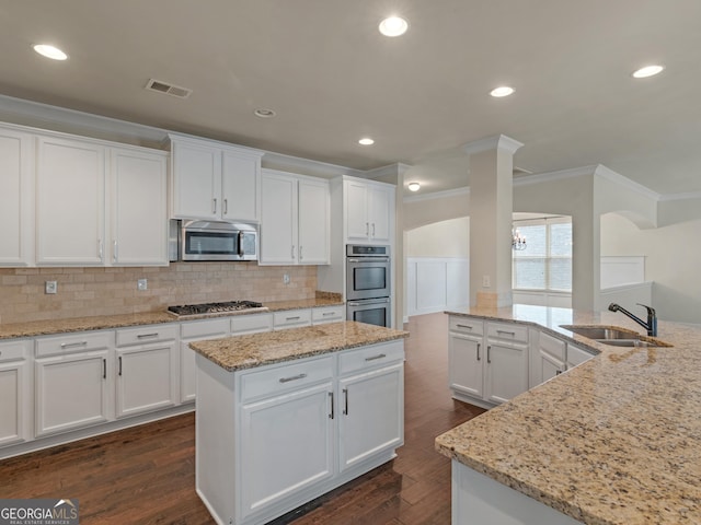 kitchen with stainless steel appliances, a kitchen island, visible vents, a sink, and white cabinetry