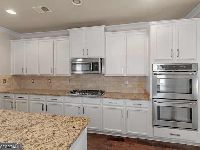 kitchen with white cabinets, visible vents, stainless steel appliances, and backsplash