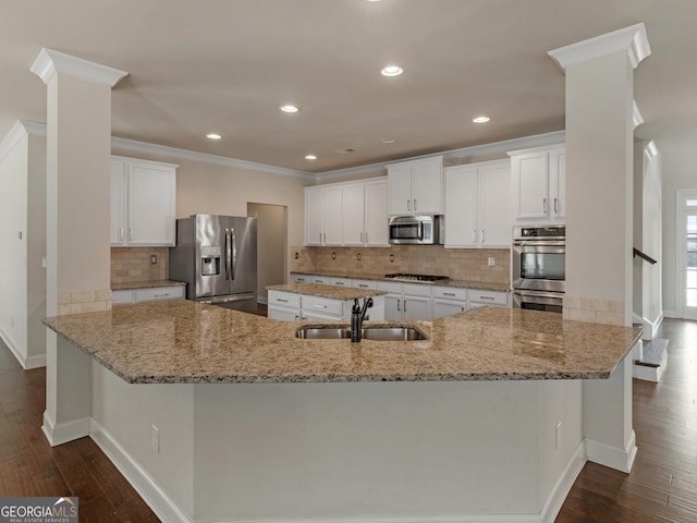 kitchen featuring appliances with stainless steel finishes, white cabinetry, a sink, and light stone counters