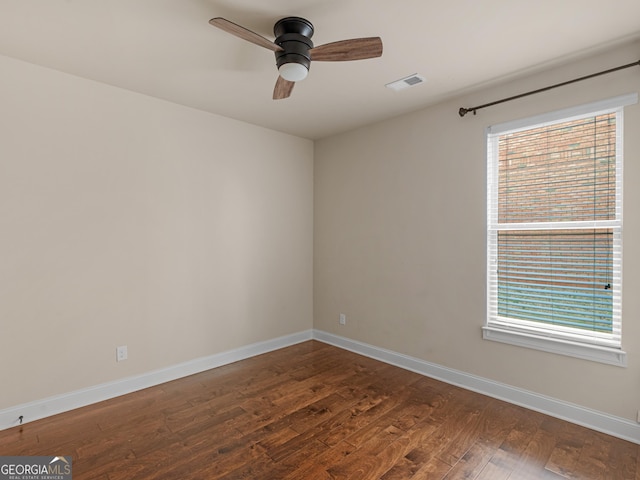 empty room featuring a ceiling fan, dark wood-style flooring, visible vents, and baseboards