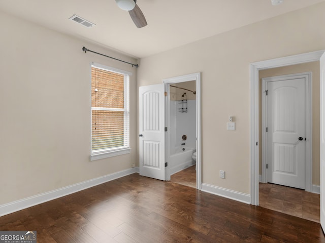 unfurnished bedroom with multiple windows, dark wood finished floors, and visible vents