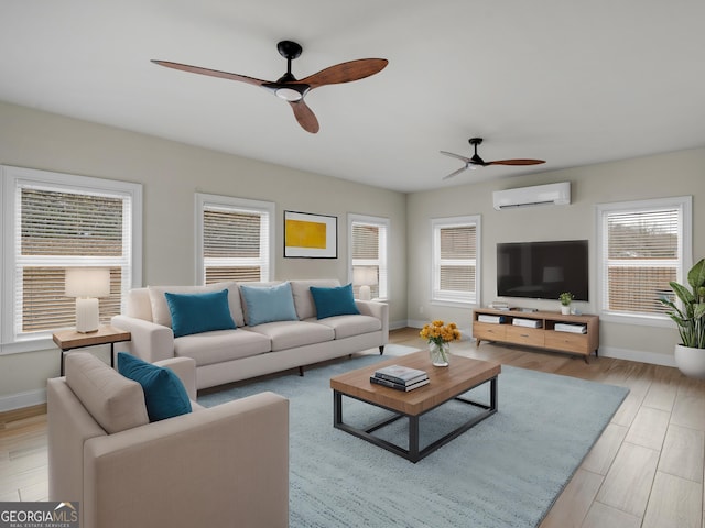 living area featuring a ceiling fan, light wood-style flooring, baseboards, and a wall mounted AC