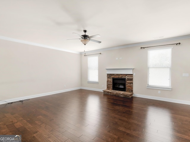 unfurnished living room with baseboards, a stone fireplace, dark wood-style flooring, and crown molding