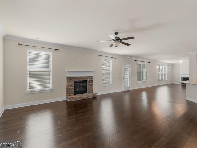 unfurnished living room with ornamental molding, dark wood finished floors, a fireplace, and a ceiling fan