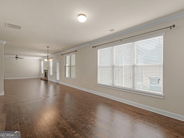 unfurnished living room with dark wood-style floors, baseboards, visible vents, and crown molding