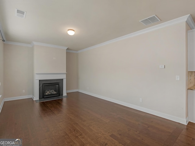 unfurnished living room with dark wood-type flooring, a fireplace with flush hearth, visible vents, and crown molding