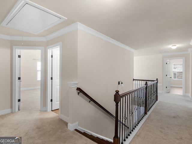 hallway with light carpet, an upstairs landing, and attic access