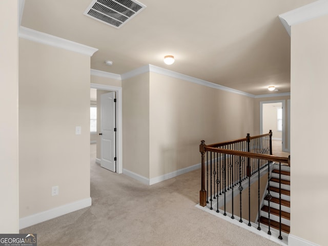 corridor featuring light colored carpet, visible vents, ornamental molding, an upstairs landing, and baseboards