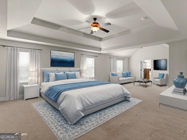 bedroom featuring light carpet, ceiling fan, and a tray ceiling