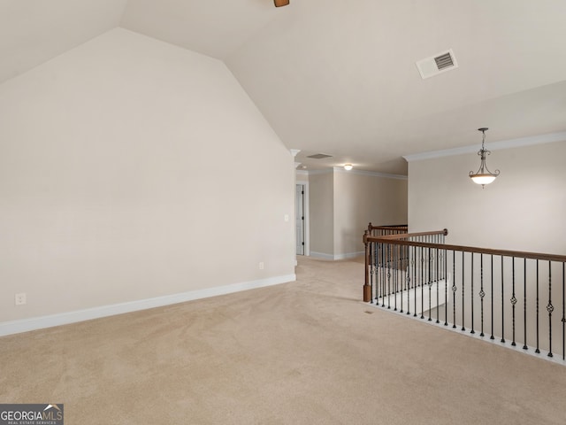 spare room with lofted ceiling, visible vents, ornamental molding, light carpet, and baseboards