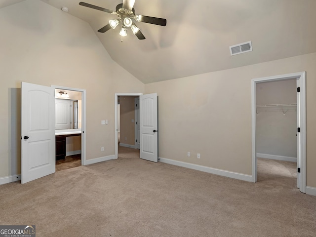 unfurnished bedroom with high vaulted ceiling, a walk in closet, visible vents, and light colored carpet