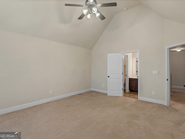 unfurnished bedroom featuring baseboards, a ceiling fan, light colored carpet, ensuite bathroom, and high vaulted ceiling