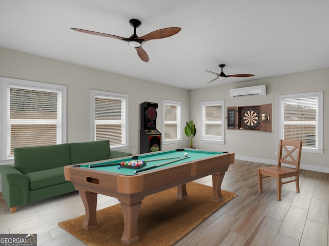 recreation room featuring light wood finished floors, baseboards, a wall unit AC, ceiling fan, and pool table