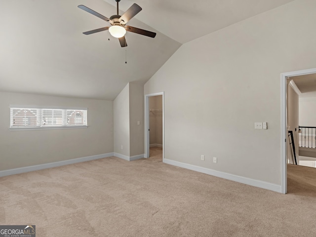 interior space featuring baseboards, a ceiling fan, light colored carpet, a spacious closet, and vaulted ceiling