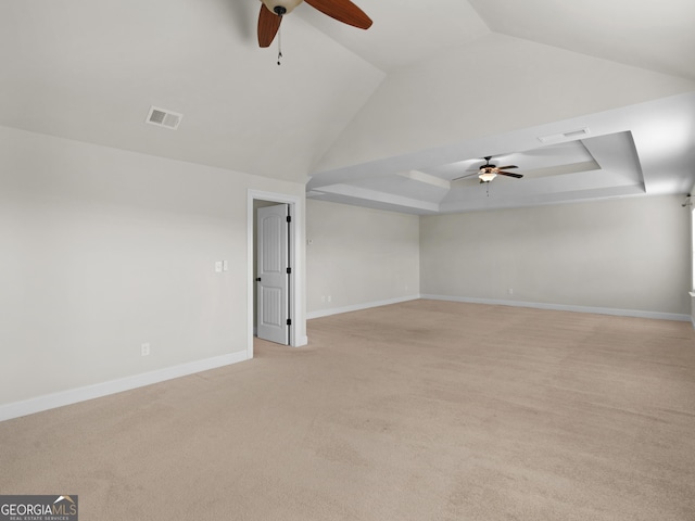 unfurnished room featuring a raised ceiling, light colored carpet, visible vents, ceiling fan, and baseboards