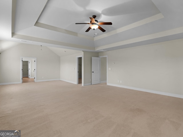 interior space with light carpet, ceiling fan, a tray ceiling, and baseboards