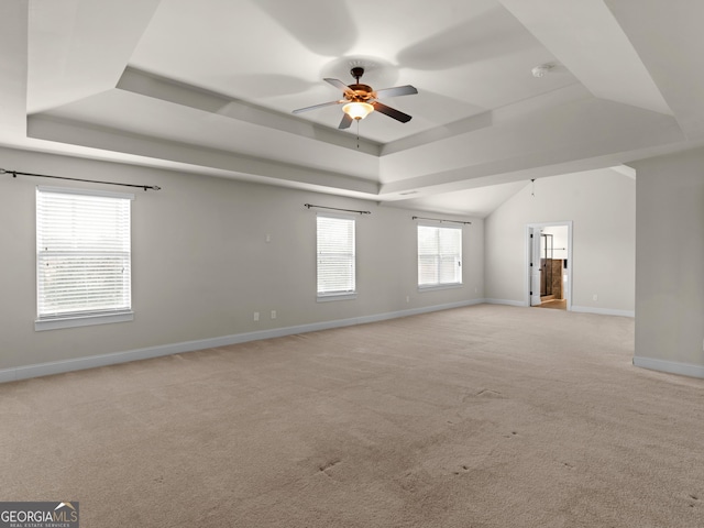 unfurnished room featuring light carpet, a tray ceiling, a ceiling fan, and baseboards