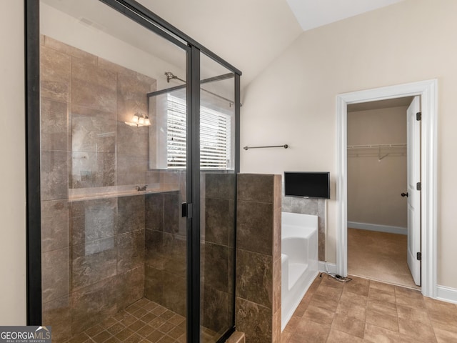 full bath featuring a stall shower, tile patterned flooring, a spacious closet, vaulted ceiling, and a bath