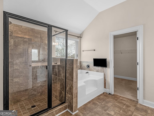 bathroom with lofted ceiling, a garden tub, a walk in closet, a shower stall, and tile walls