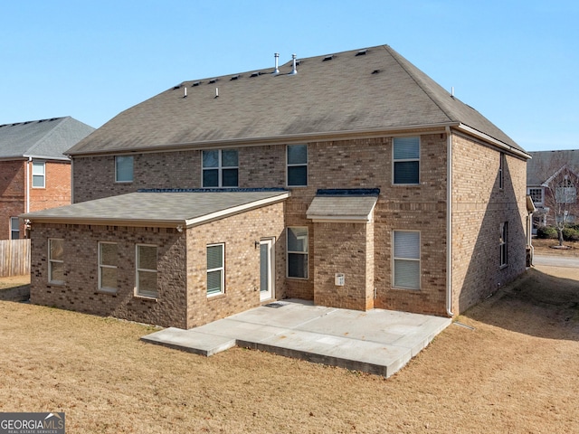 back of property with a patio, brick siding, a lawn, and roof with shingles