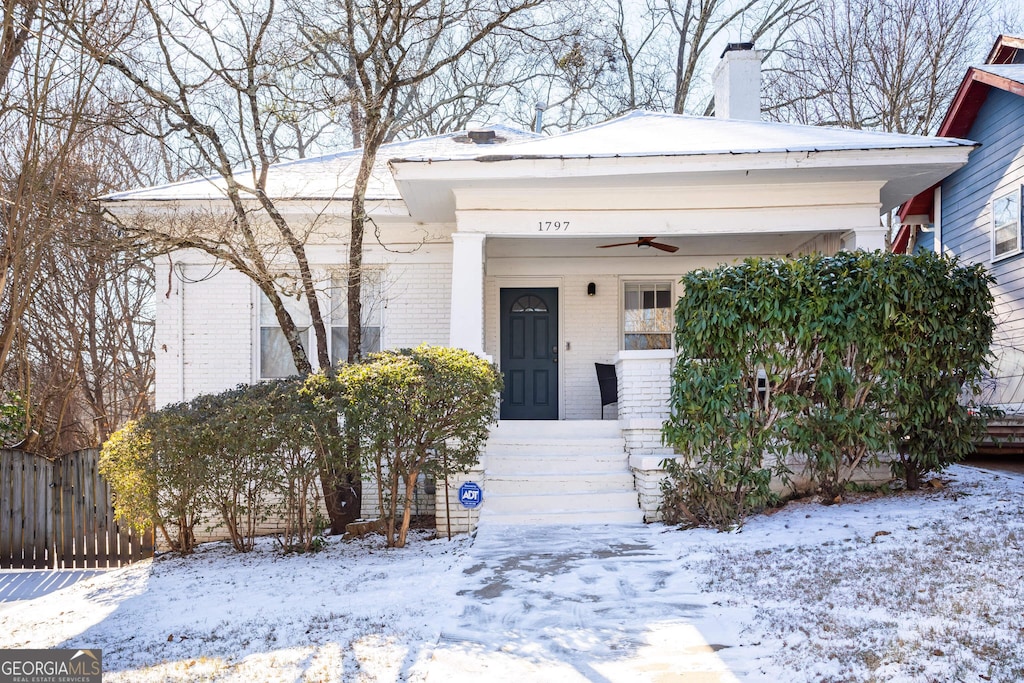 snow covered property entrance with covered porch and ceiling fan