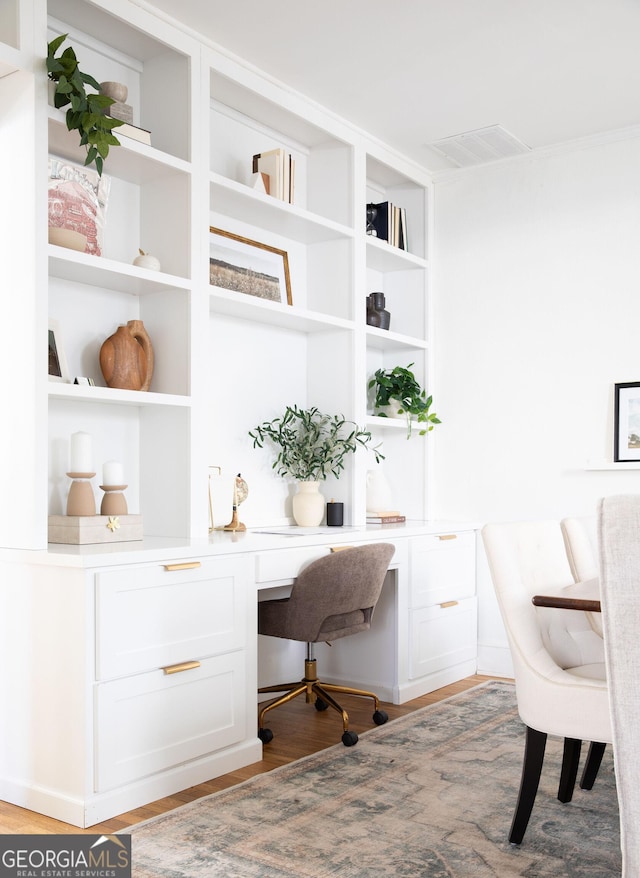 office space with built in desk and light wood-type flooring