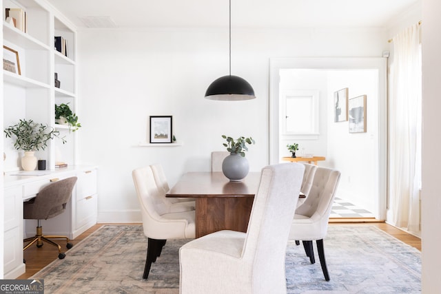 dining area with built in shelves and light hardwood / wood-style flooring