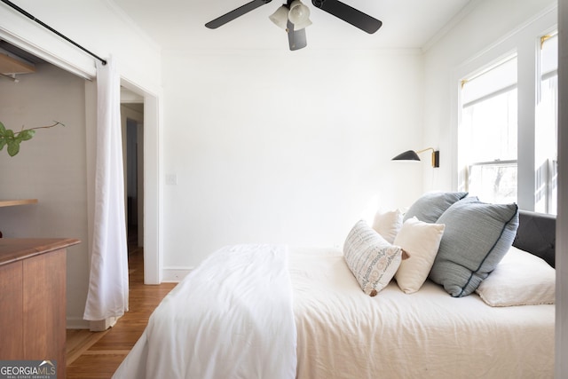 bedroom featuring hardwood / wood-style flooring, ceiling fan, and crown molding