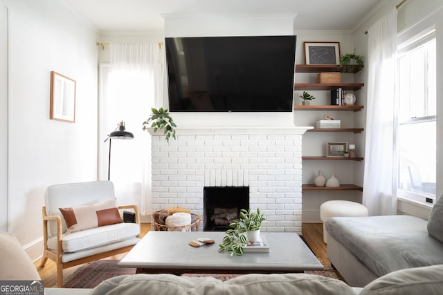 living room featuring crown molding, plenty of natural light, hardwood / wood-style floors, and a brick fireplace