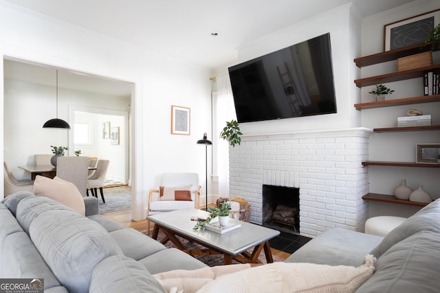 living room featuring a brick fireplace, ornamental molding, and light wood-type flooring