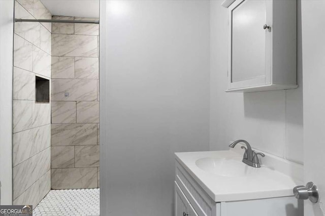 bathroom featuring a tile shower and vanity