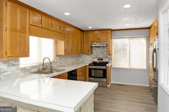 kitchen with black appliances, light wood-type flooring, sink, kitchen peninsula, and ornamental molding