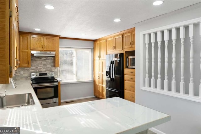 kitchen with appliances with stainless steel finishes, sink, backsplash, kitchen peninsula, and crown molding