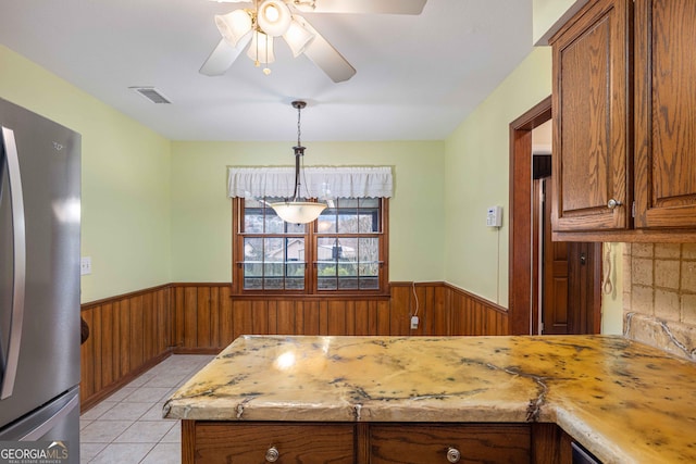 kitchen featuring ceiling fan, pendant lighting, stainless steel refrigerator, and light tile patterned floors