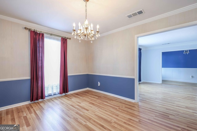 spare room with crown molding, a notable chandelier, and light wood-type flooring