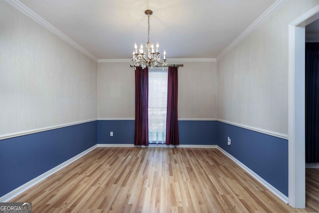 empty room featuring ornamental molding, a chandelier, and light wood-type flooring