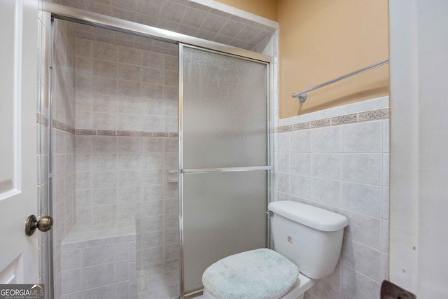 bathroom featuring toilet, tile walls, and a shower with shower door