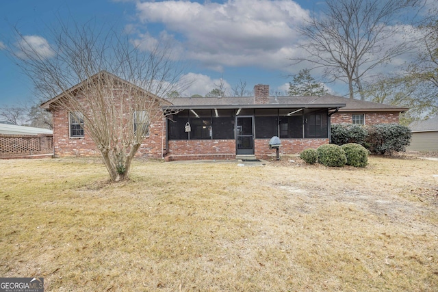 rear view of property featuring a sunroom and a lawn