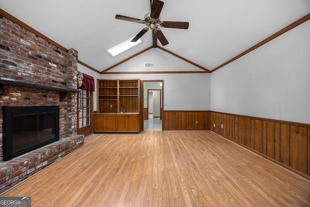 unfurnished living room with lofted ceiling, ceiling fan, hardwood / wood-style floors, ornamental molding, and a brick fireplace