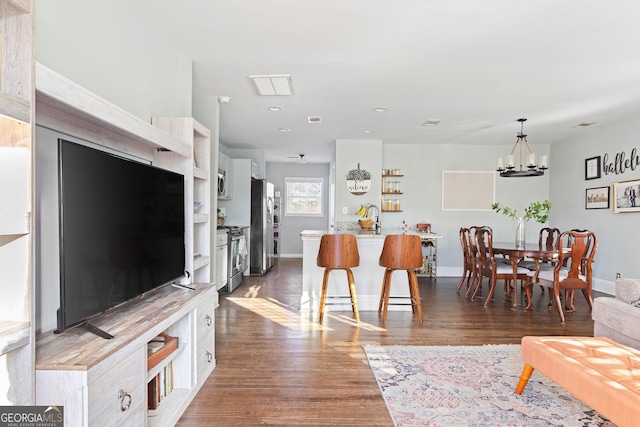 living room with an inviting chandelier and dark wood-type flooring