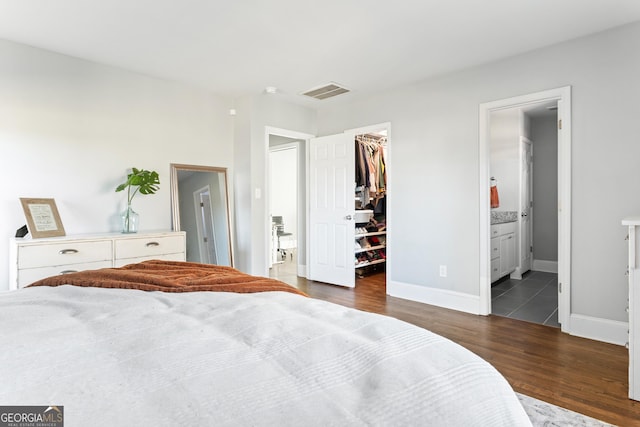 bedroom featuring a spacious closet, dark wood-type flooring, a closet, and ensuite bathroom