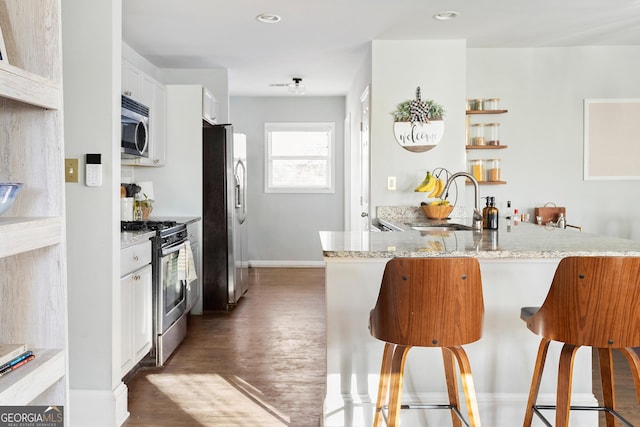 kitchen with stainless steel appliances, kitchen peninsula, white cabinets, and a breakfast bar