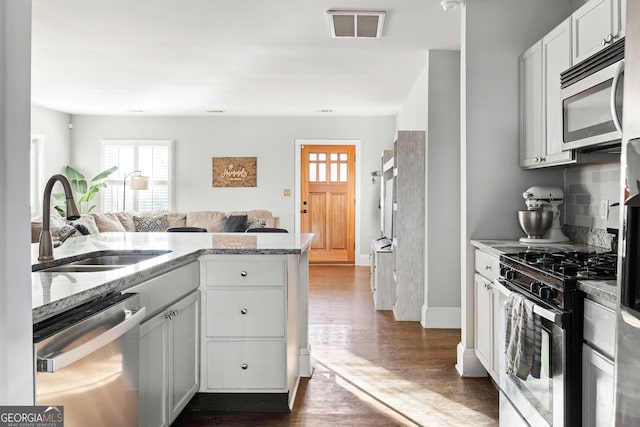 kitchen featuring sink, appliances with stainless steel finishes, backsplash, dark hardwood / wood-style floors, and white cabinets