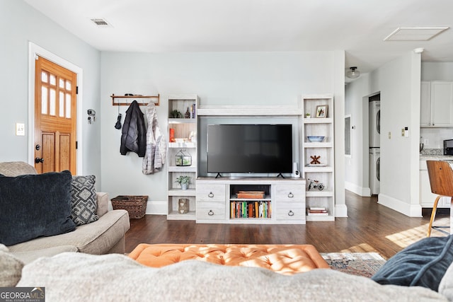 living room with dark hardwood / wood-style floors and stacked washing maching and dryer