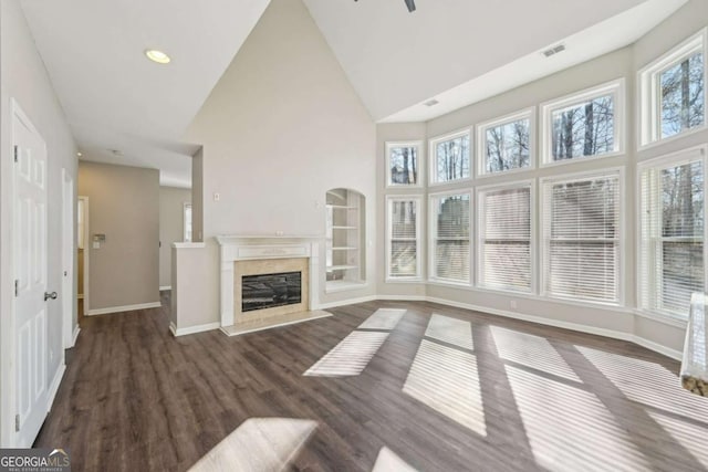 unfurnished living room with high vaulted ceiling, a high end fireplace, dark hardwood / wood-style flooring, and a healthy amount of sunlight