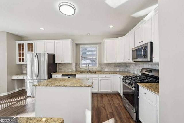 kitchen with white cabinets, appliances with stainless steel finishes, sink, and a kitchen island